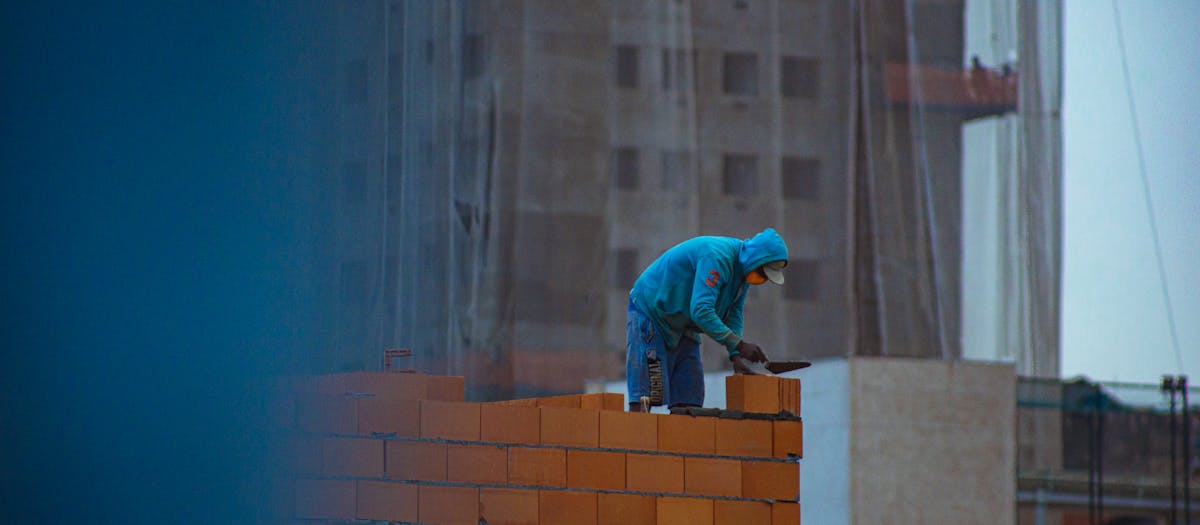 Construction worker core drilling through external brick masonry wall